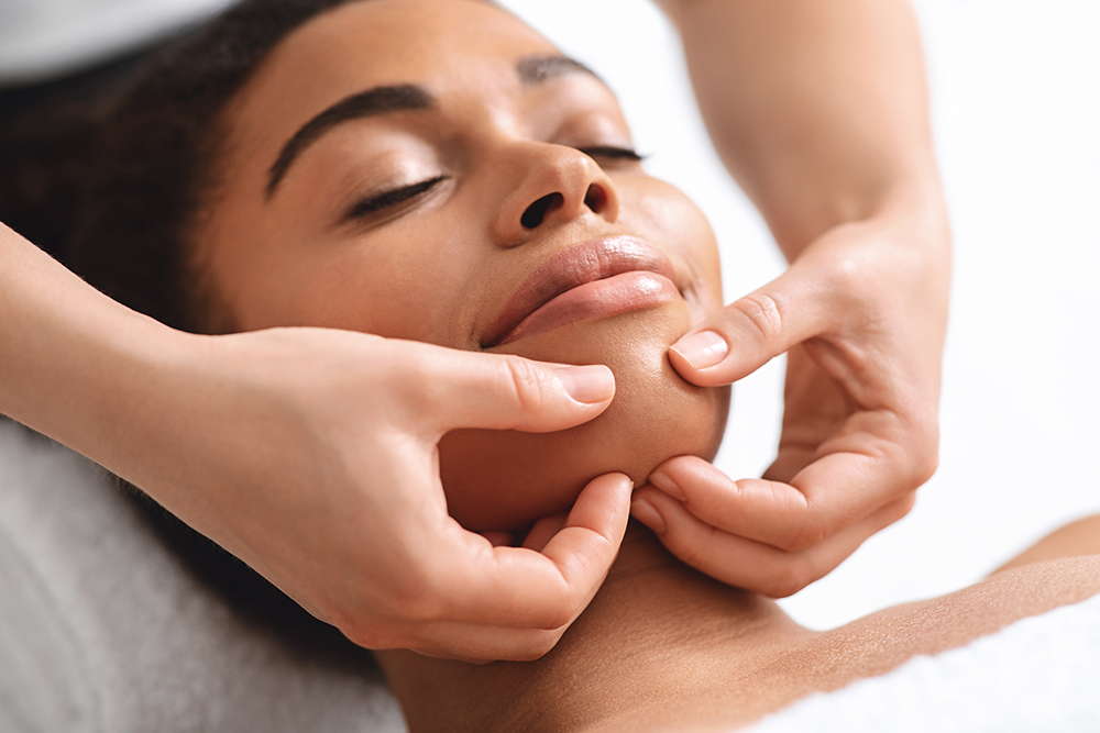 Massage therapist rubbing relaxed black lady chin Massage therapist rubbing relaxed black lady chin